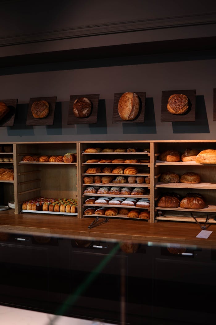 A wooden shelf filled with a variety of freshly baked breads in a bakery setting.