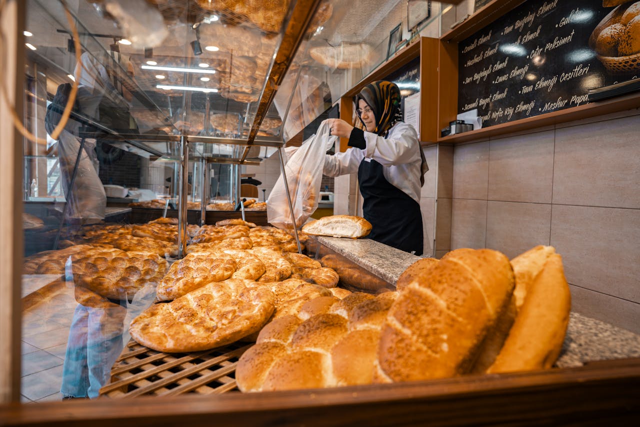 Baker packaging fresh, golden-brown bread in a vibrant bakery setting.